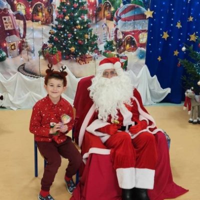Chłopiec z rogami renifera pozuje do zdjęcia z Mikołajem