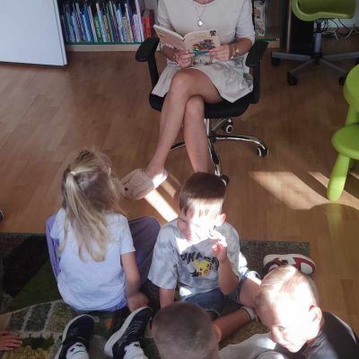Dzieci słuchające bajki czytanej przez bibliotekarkę