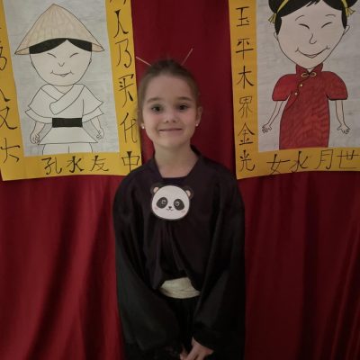 Dziewczynka pozuje na tle rysunków w azjatyckim przebraniu