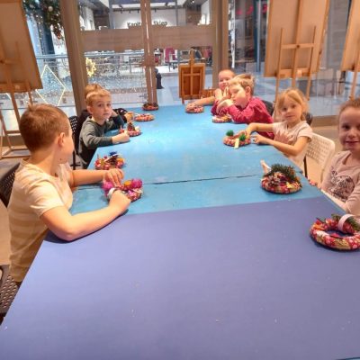 Dzieci siedzą przy stole ze swoimi ozdobami